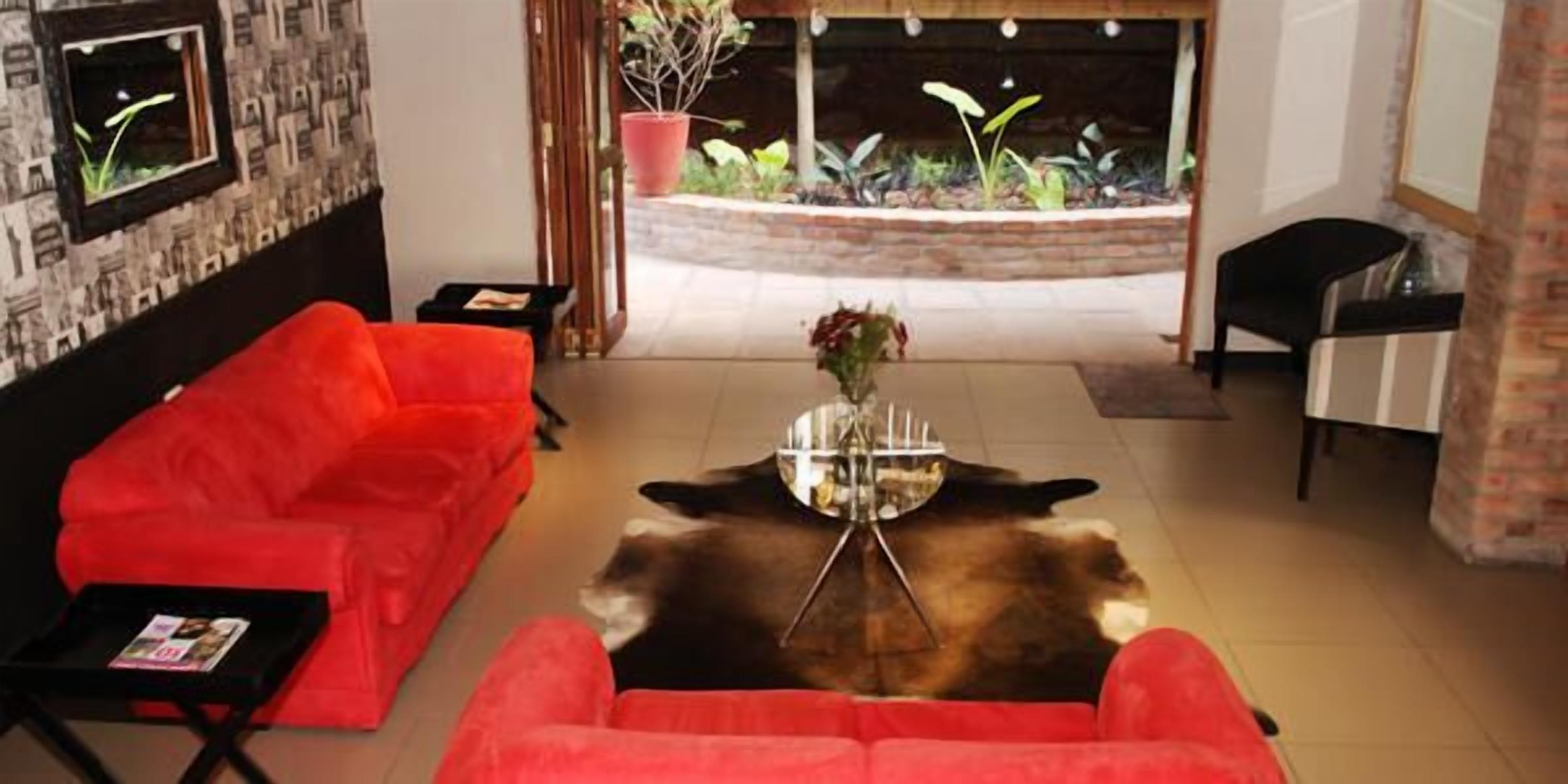 A living room with a red sofa, a glass coffee table, and a small potted plant.