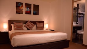 A hotel room with a large bed, two bedside tables, and a nightstand. There are three framed pictures on the wall above the bed. - Mirador del Monasterio (Arequipa)