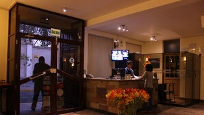 A hotel lobby with a reception desk, a large screen, and a glass door entrance. - Mirador del Monasterio (Arequipa)