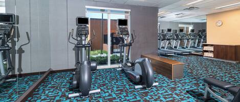 A gym with treadmills, elliptical machines, and a bench.