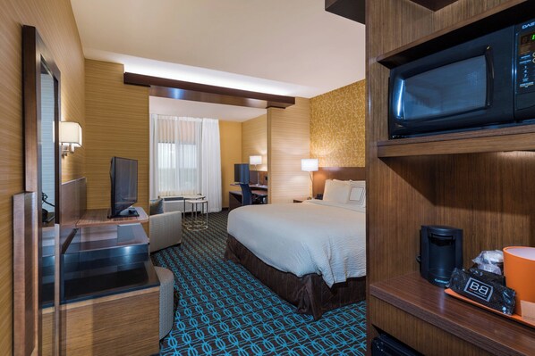 Een hotelkamer met een bed, bureau, televisie en magnetron.