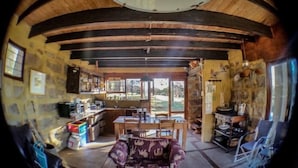 Una cocina rústica con paredes de piedra, vigas de madera y un comedor con un sofá estampado.