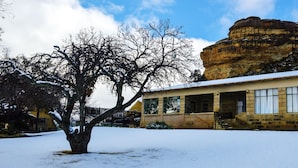 Un edificio de piedra con un paisaje nevado y una gran formación rocosa al fondo.