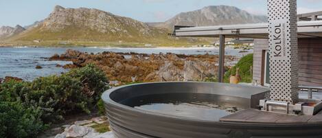 A hot tub with a view of the sea and mountains.