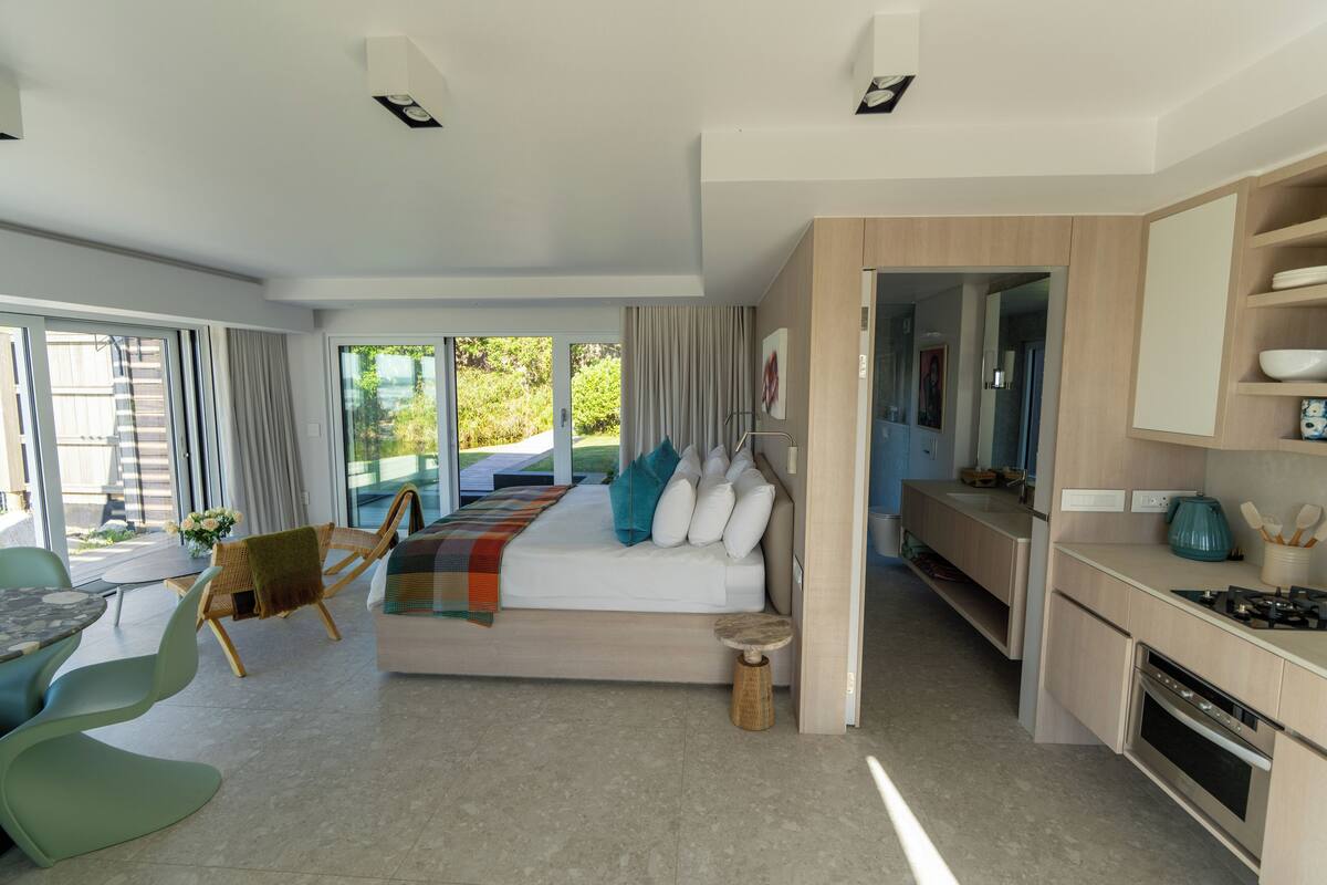 A modern interior with a bed, seating area, and kitchen.