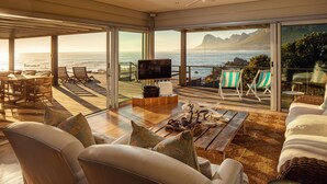 A spacious living area with a large TV, comfortable seating, and a view of the ocean. - Pringle Bay Villa (Pringle Bay)
