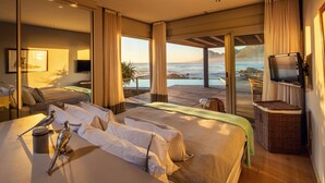 A modern hotel room with a large bed, a TV, and a view of the ocean. - Pringle Bay Villa (Pringle Bay)