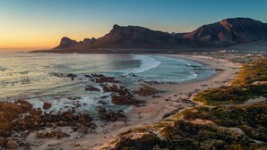 A coastal landscape with a beach, rocky outcrops, and a mountain in the background. - Pringle Bay Villa (Pringle Bay)