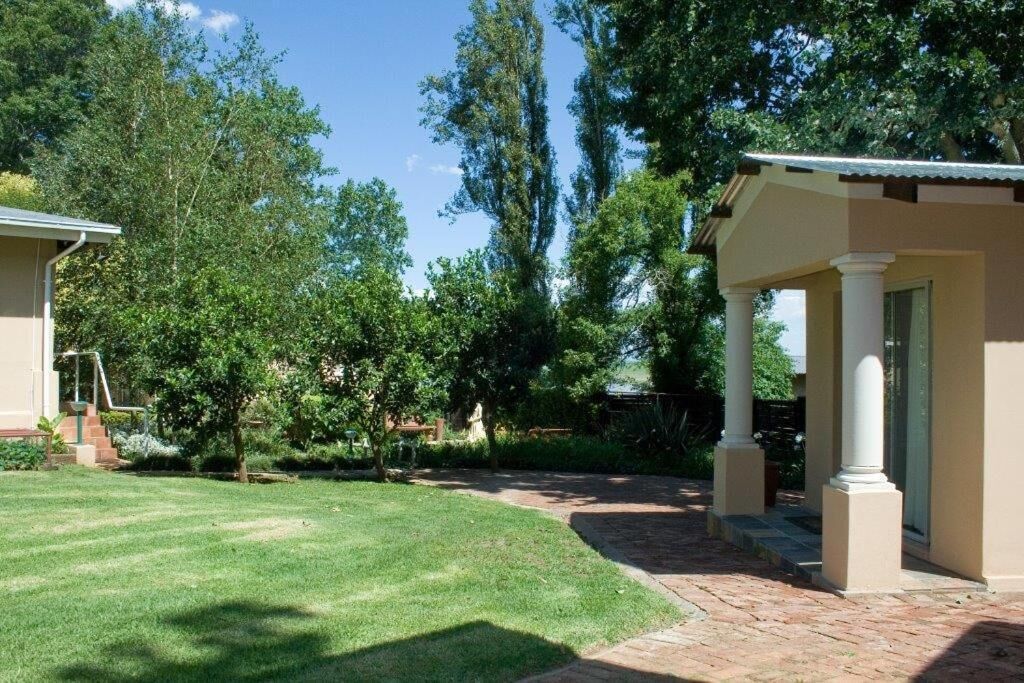 A residential property with a well-maintained lawn, a brick pathway, and a covered patio area with columns.