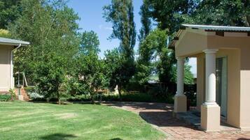 A residential property with a well-maintained lawn, a brick pathway, and a covered patio area with columns.