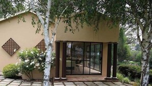 A building with a beige exterior, a glass door entrance, and a paved pathway leading to it.