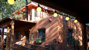 A rustic building with a wooden facade, a balcony with a railing, and hanging spherical lights. - Inn at Halona (Zuni)
