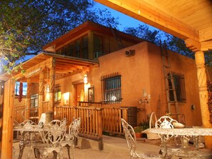 A rustic building with a covered patio, outdoor seating, and a wooden staircase. - Inn at Halona (Zuni)