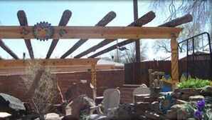 A wooden pergola structure with a decorative top, surrounded by rocks and garden elements. - Inn at Halona (Zuni)