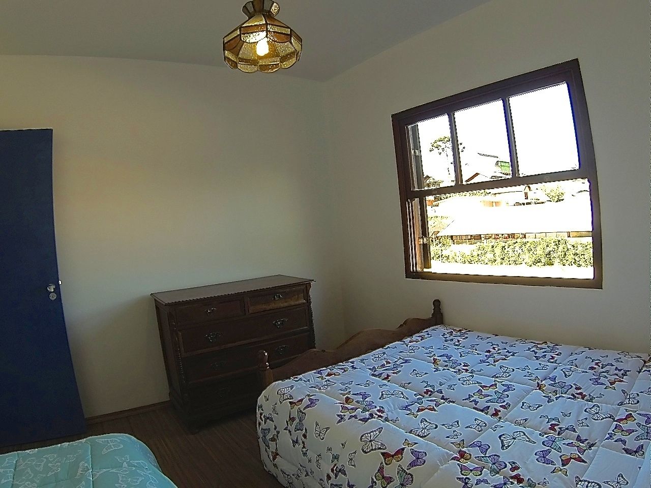 A bedroom with a bed, a dresser, a window, and a ceiling light.