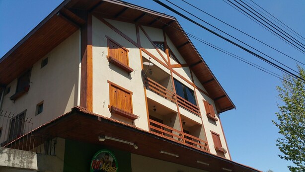 A two-story building with a balcony on the second floor, a green awning, and a sign with the text "FUT Maria". - Apartamento dois quartos Capivarí (Campos do Jordão)