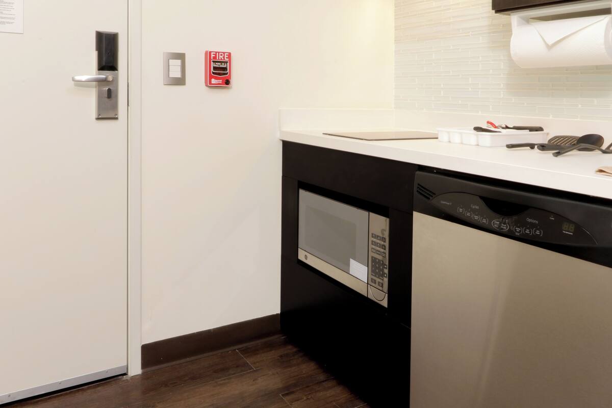 Une cuisine équipée d’un four à micro-ondes, d’un lave-vaisselle et d’un détecteur d’incendie fixé au mur.