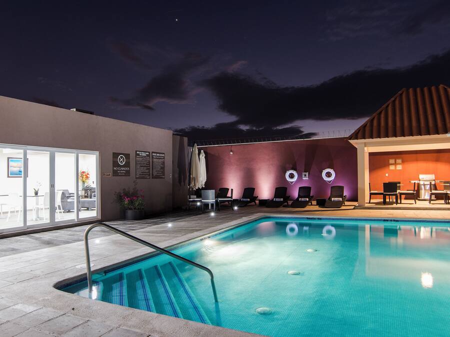 Een buitenzwembad, parasols bij het zwembad en ligstoelen