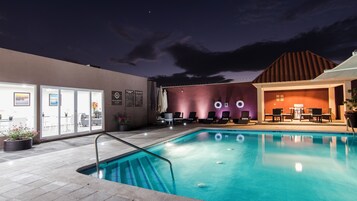 Una piscina al aire libre, sombrillas, sillones reclinables de piscina