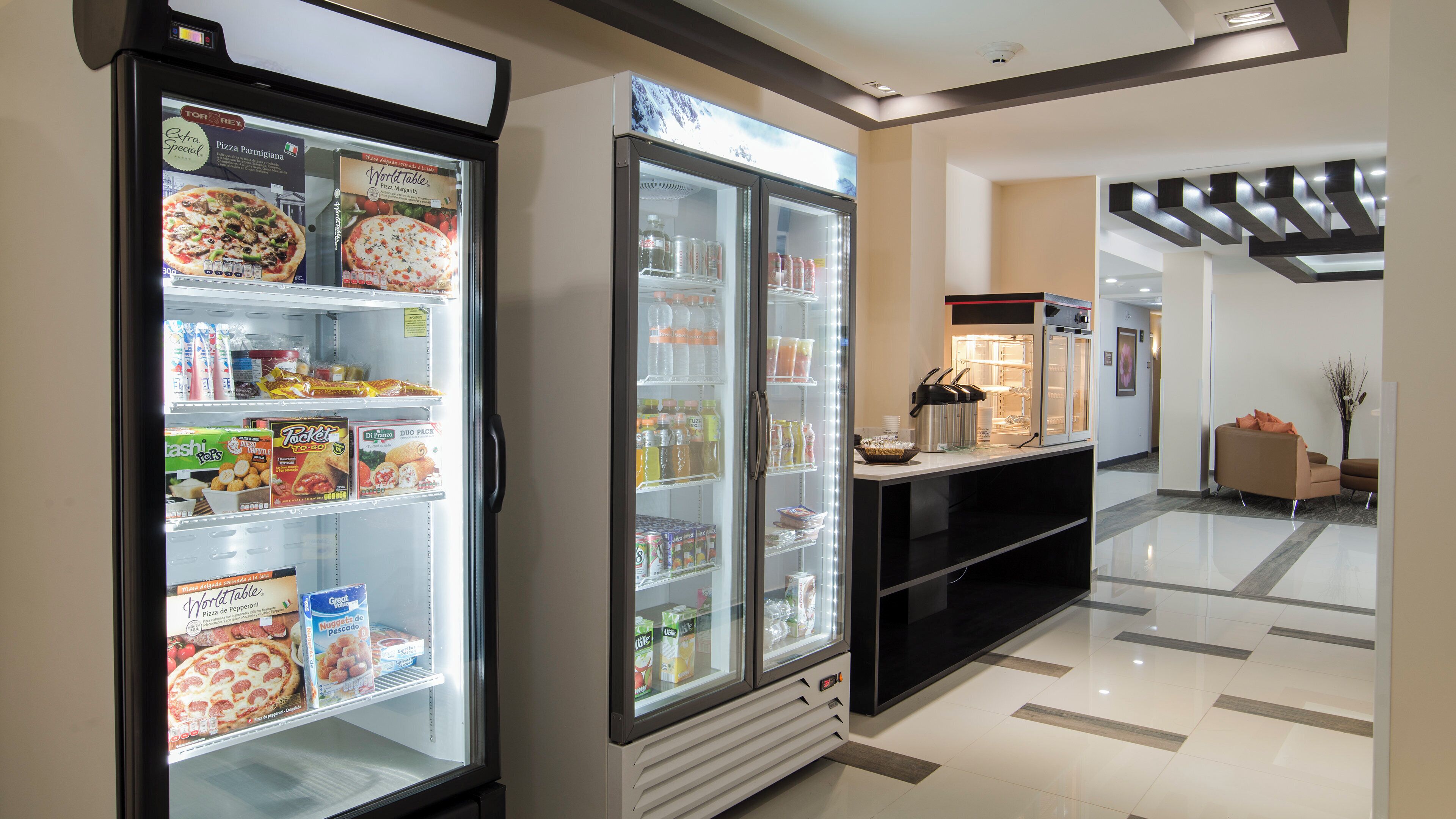 A hotel lobby with a self-service beverage station and refrigerated display cases.