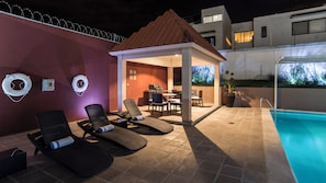 Un espace piscine extérieur avec des chaises longues, un coin salon abrité et une bouée de sauvetage.