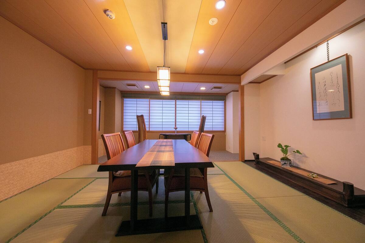 Ein traditioneller japanischer Besprechungsraum mit Tatami-Böden, einem niedrigen Tisch und Holzstühlen.
