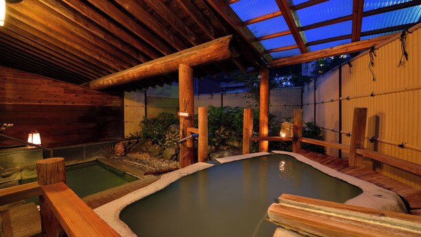 A traditional Japanese onsen with wooden structures and a glass ceiling. - Wakamatsuya (Yamagata)