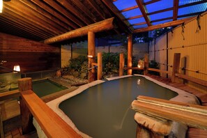 Un onsen japonés tradicional con estructuras de madera y techo de cristal.