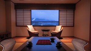 A room with a large window, two wicker chairs, a table with a placemat, and two cups. - Wakamatsuya (Yamagata)
