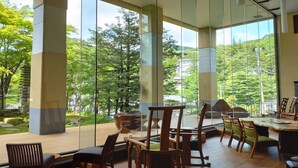 A modern indoor space with large glass windows, wooden furniture, and a view of a lush green landscape. - Wakamatsuya (Yamagata)