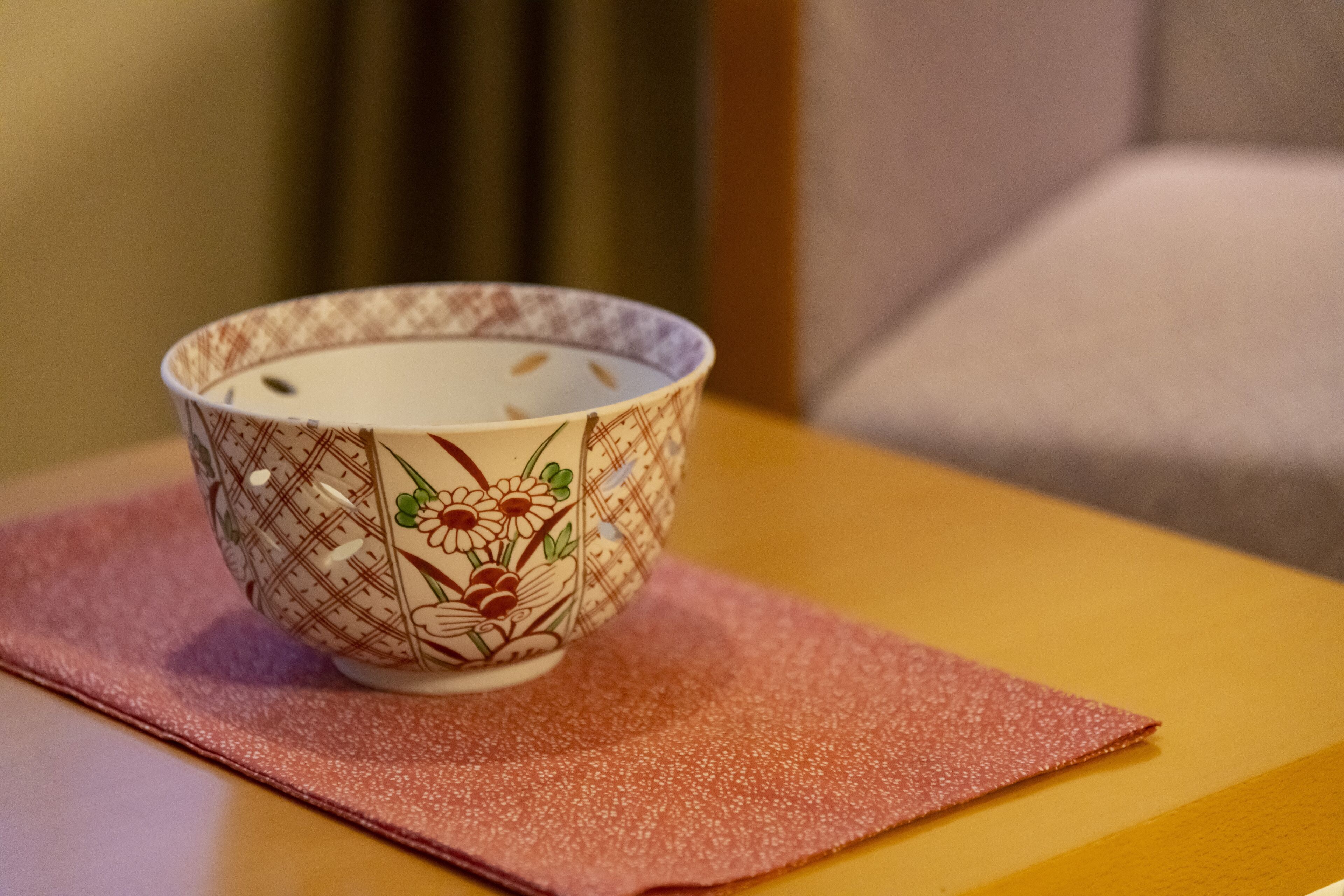 Un bol orné de motifs floraux, posé sur une table recouverte d’une nappe rose.