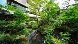 A serene indoor garden with a water feature, surrounded by lush greenery and traditional architecture. - Senkeien Tsukioka Hotel (Kaminoyama)