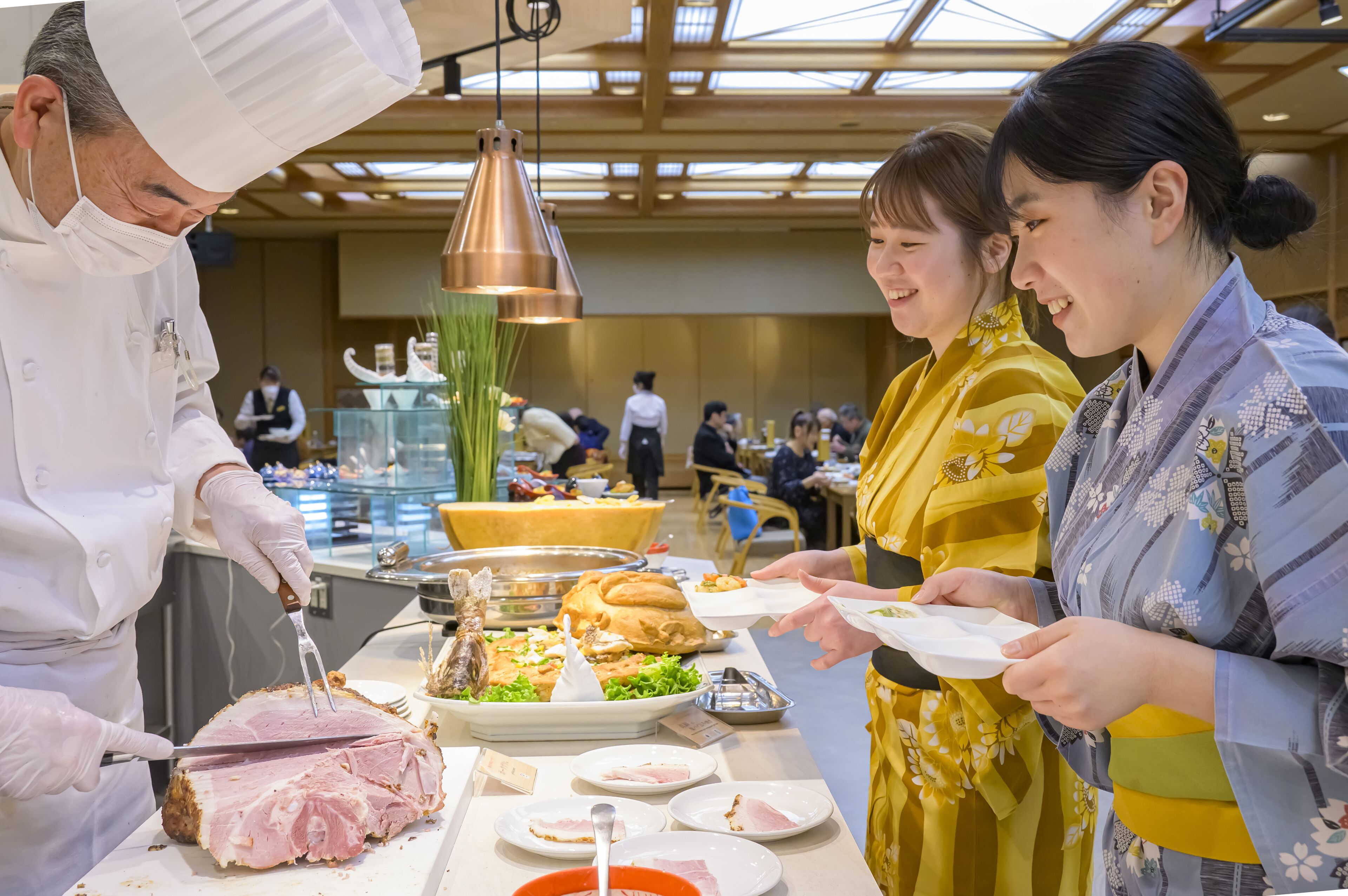 Un chef tranchant de la viande à une table de buffet, avec divers plats et une vitrine en verre en arrière-plan.