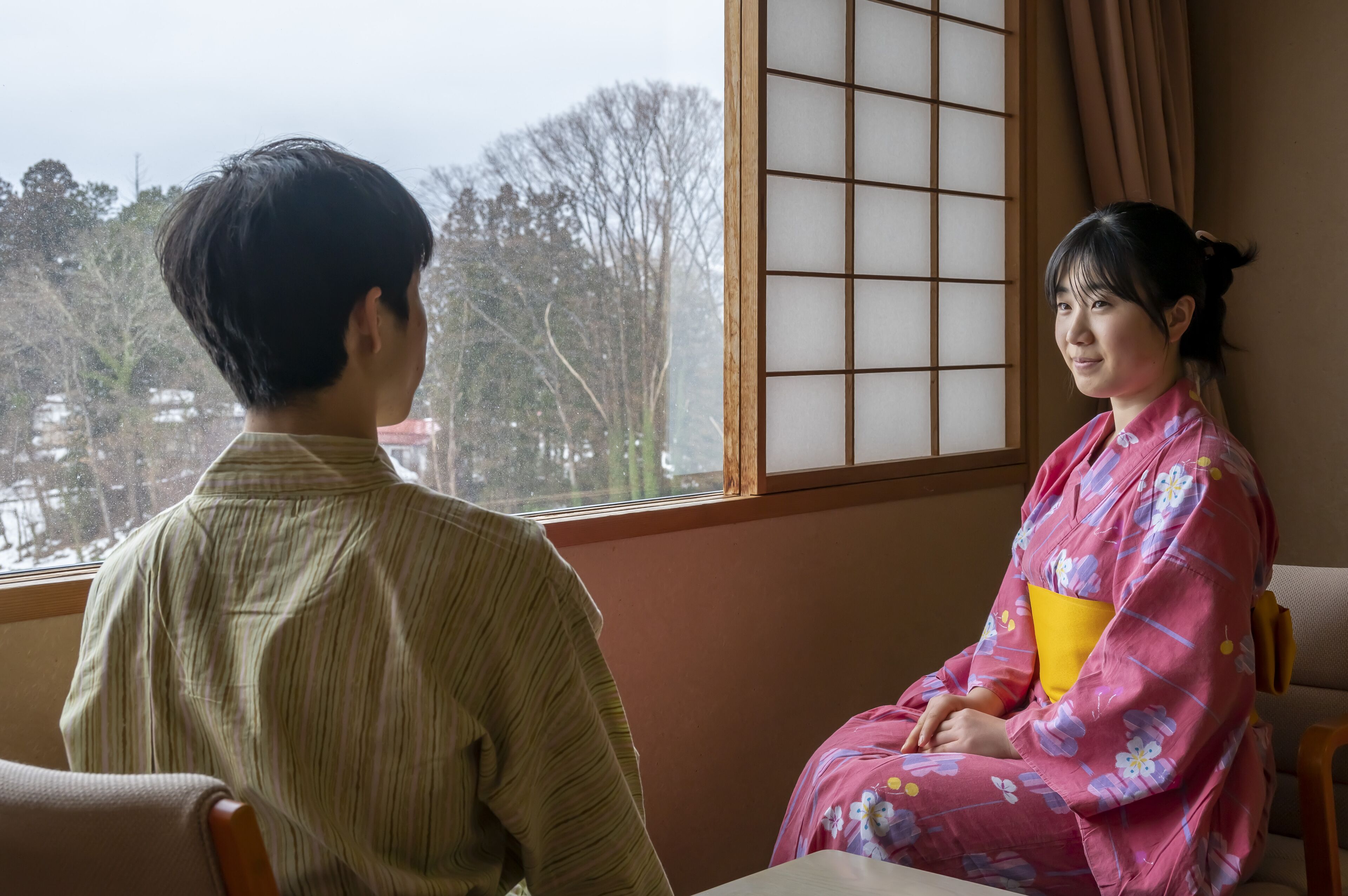 A room with a large window, a traditional sliding door, and a view of trees outside.