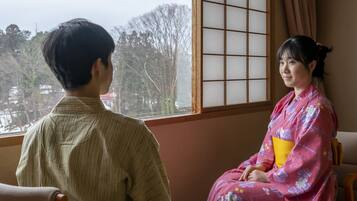 A room with a large window, a traditional sliding door, and a view of trees outside.