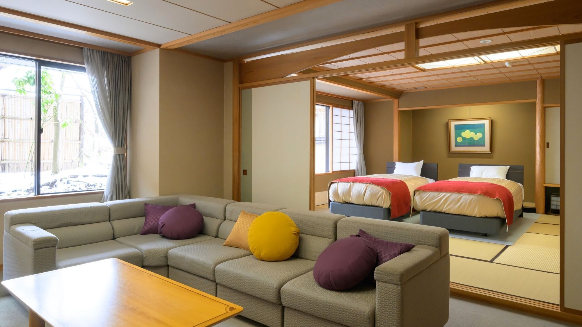 Habitación de hotel con sofá, cama, suelo de tatami y vistas al exterior.