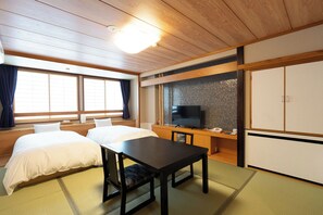 A traditional Japanese room with tatami flooring, a bed, a desk, and a television. - Arimakan (Kaminoyama)