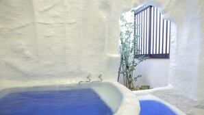 A white-walled room with a large bathtub and a smaller one. There is a window with black and white shutters. - Arimakan (Kaminoyama)