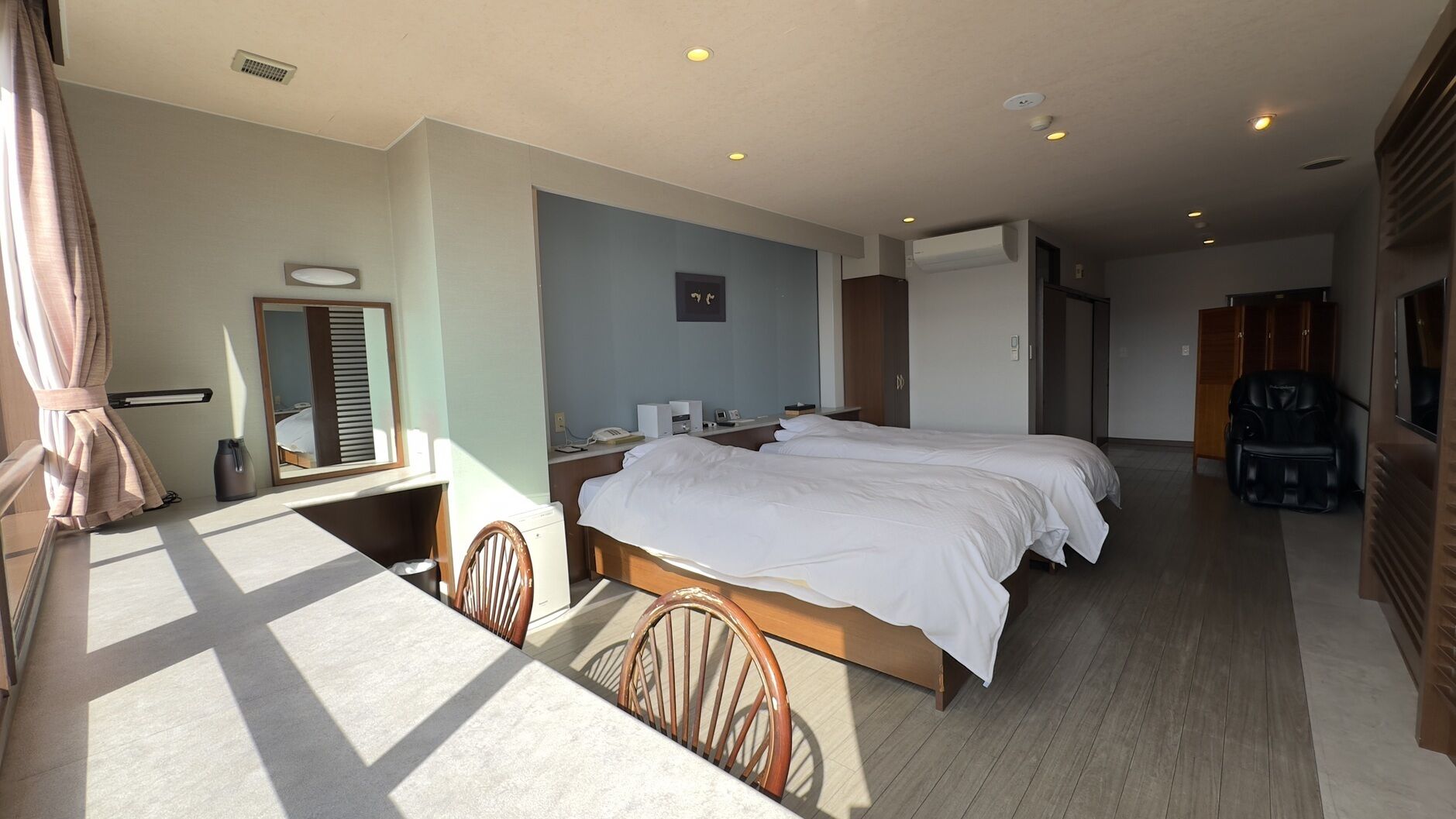Habitación de hotel con una cama grande, un escritorio, una silla, un espejo y un armario.
