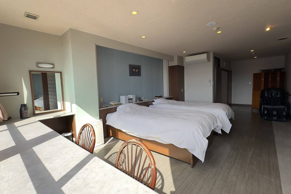Une chambre d’hôtel avec un grand lit, un bureau, une chaise, un miroir et une armoire.