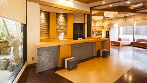 A reception area with a stone wall, wooden reception desk, and seating area. - Arimakan (Kaminoyama)