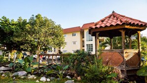 A gazebo with a tiled roof, surrounded by lush greenery and rocks. - Kingston Guest Apt at Plantation Springs (Kingston)