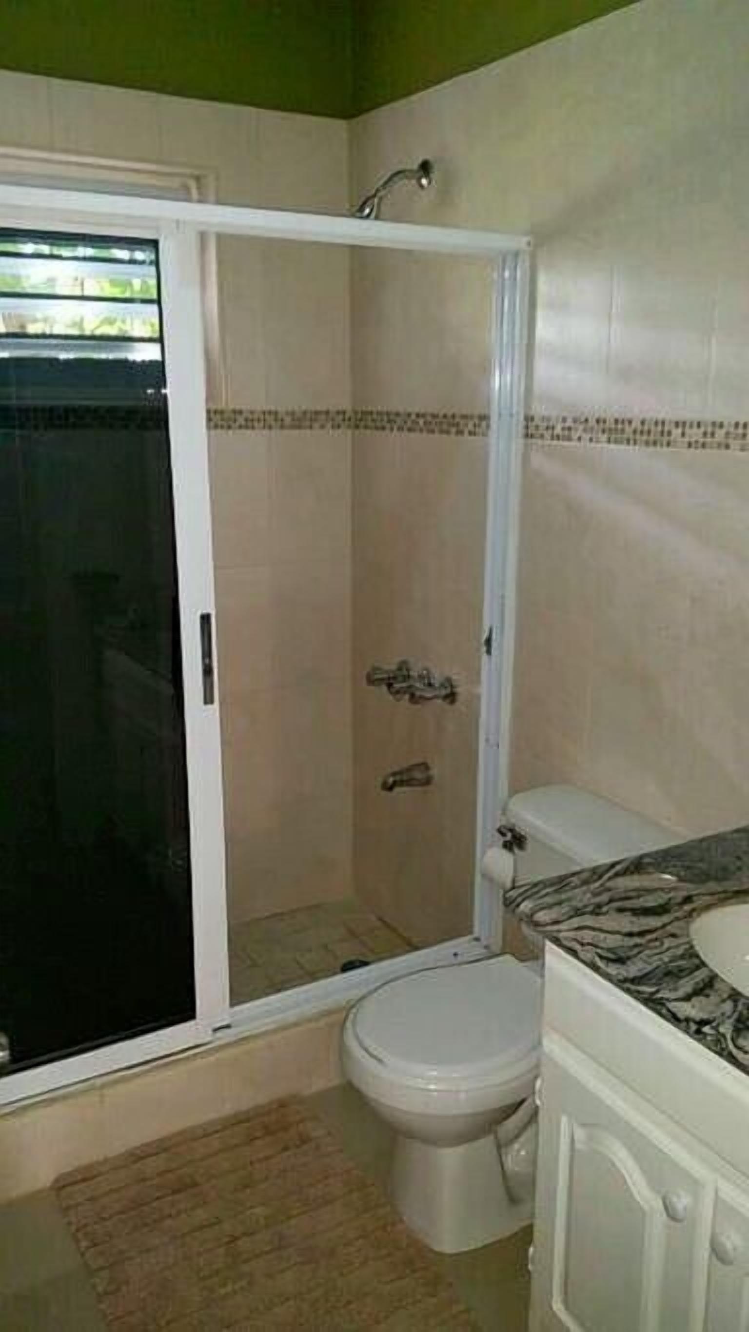 A bathroom with a shower enclosure, toilet, and vanity.