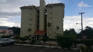 A multi-story building with a central staircase, a red-tiled roof, and a white fence surrounding the property. - Oaklands Guest Oasis (Kingston)