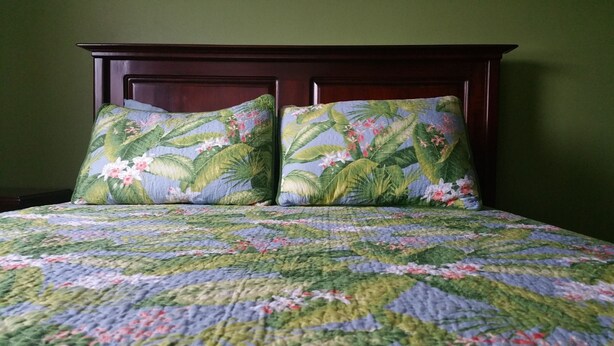 A bed with a floral patterned bedspread and two matching pillows. - Oaklands Guest Oasis (Kingston)