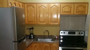 A kitchen with wooden cabinets, a stainless steel refrigerator, a sink, and a stove. - Oaklands Guest Oasis (Kingston)