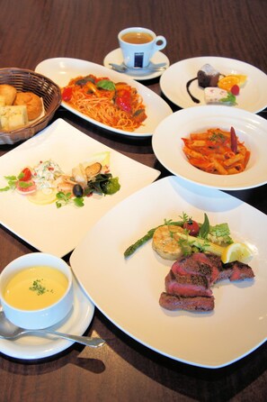 A table with various dishes including pasta, steak, and soup. - Hotel Bestland (Tsukuba)