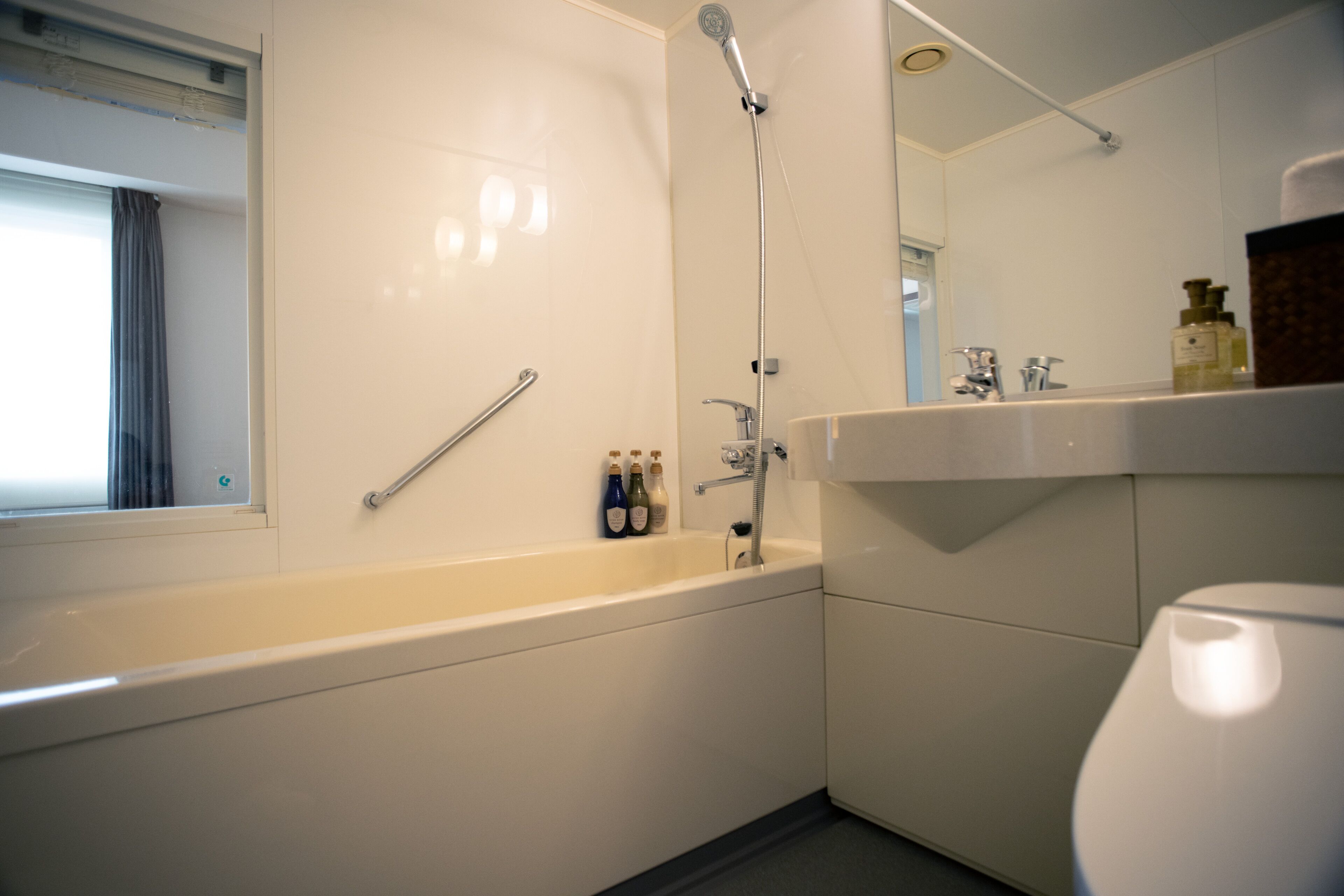 A modern bathroom with a bathtub, shower, and toilet.