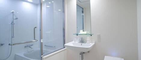 A modern bathroom with a glass-enclosed shower, a white sink, and a toilet.