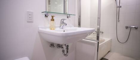 A modern bathroom with a white sink, a glass shelf, a mirror, a shower, and a toilet.